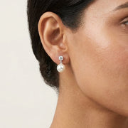 Woman wearing pearl earrings with a neutral background